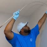 air duct cleaning worker inserting vacuum hose into vent